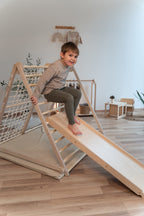 Kind rutscht auf der CLIFF Rutschrampe aus Naturholz im Kinderzimmer
