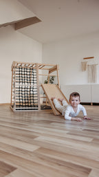 Kind rutscht auf dem Bauch auf der CLIFF Rutschrampe aus Naturholz im Kinderzimmer