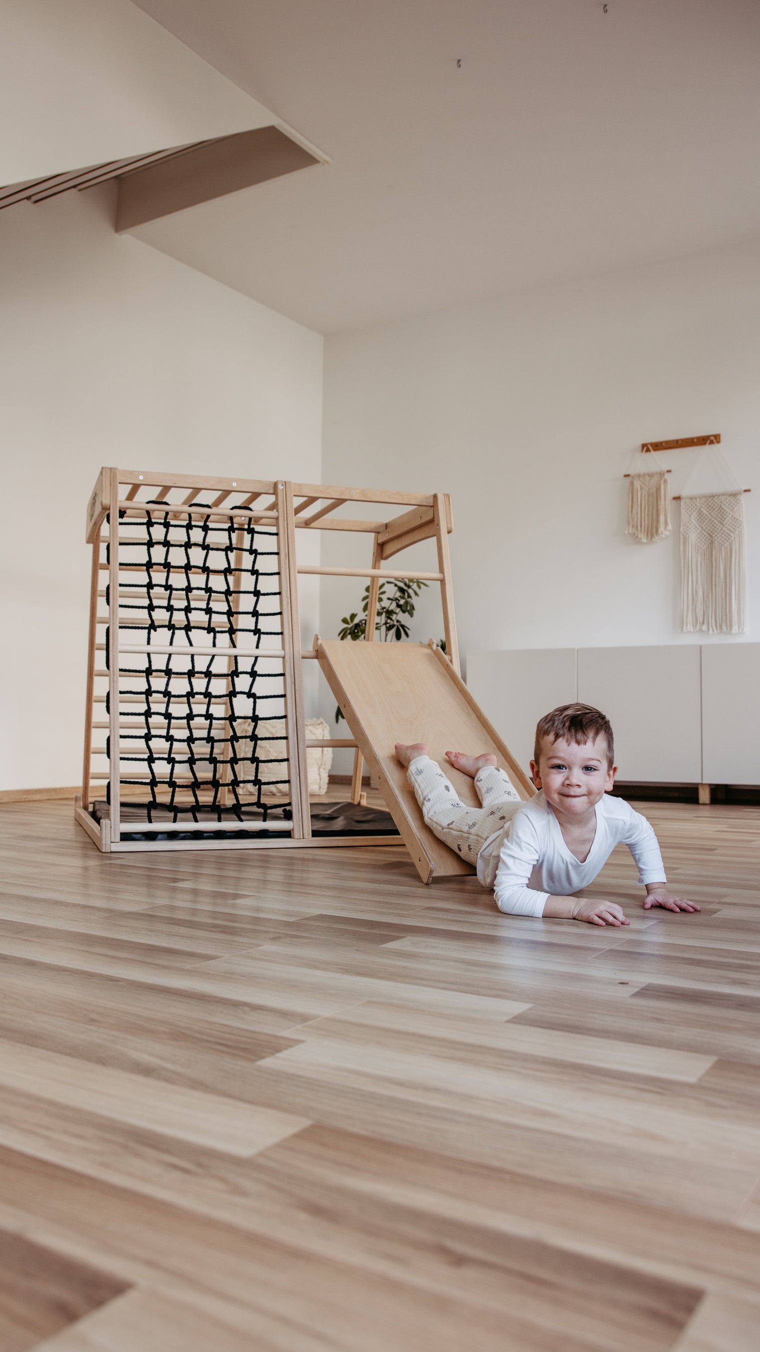 Kind rutscht auf dem Bauch auf der CLIFF Rutschrampe aus Naturholz im Kinderzimmer
