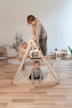 Mehrere Kinder spielen gemeinsam am CLIFF FLEX White Edition Klettergerüst mit Premium-Matte