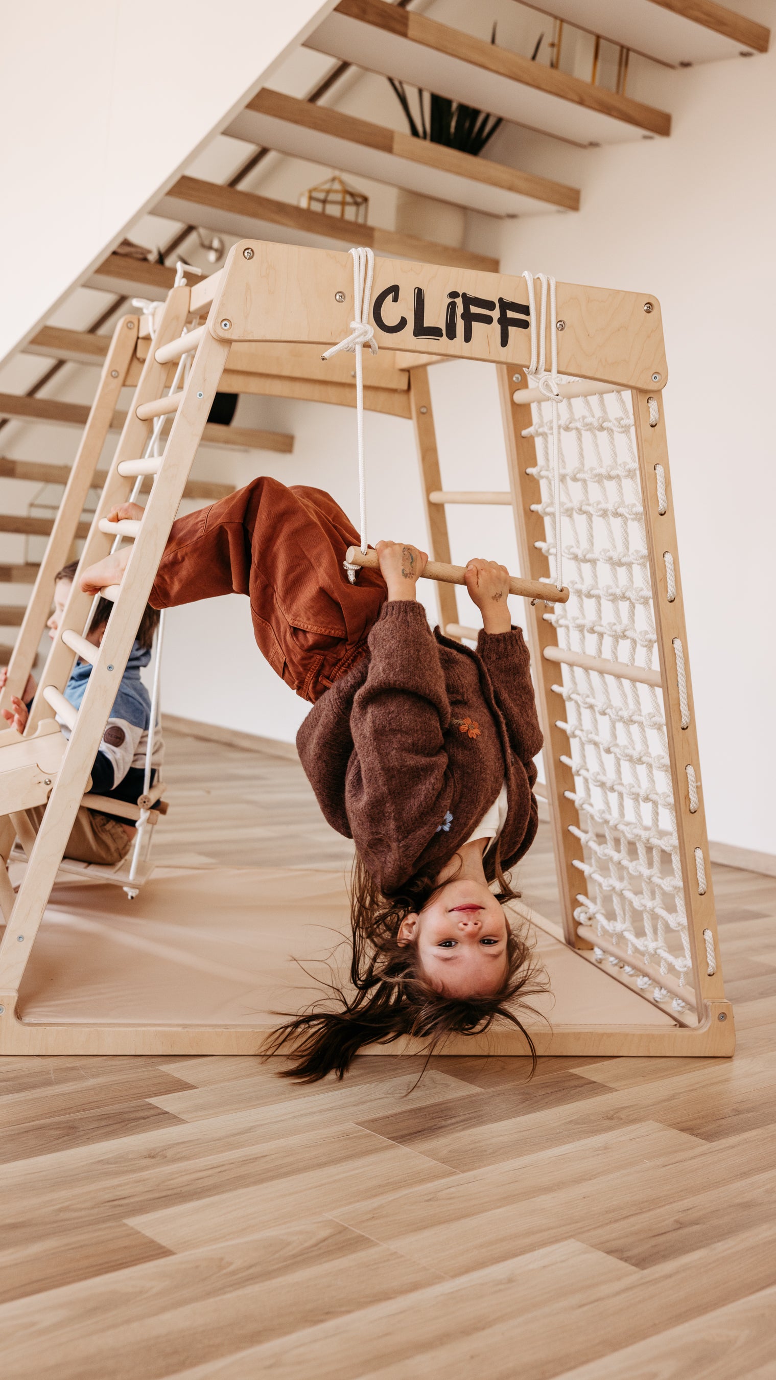 Kind hängt kopfüber am CLIFF Holztrapez aus Naturholz