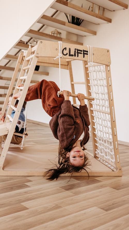 Kind hängt kopfüber am CLIFF Holztrapez aus Naturholz