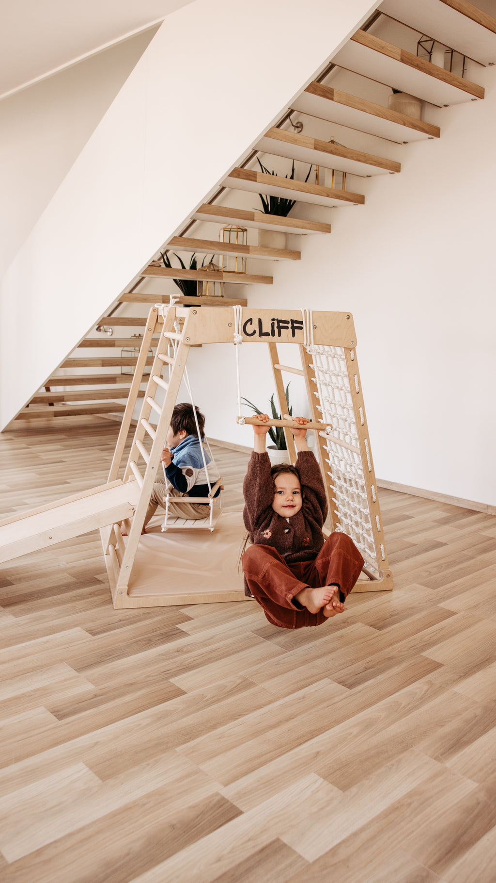 Kinder nutzen das CLIFF Holztrapez am Indoor-Klettergerüst