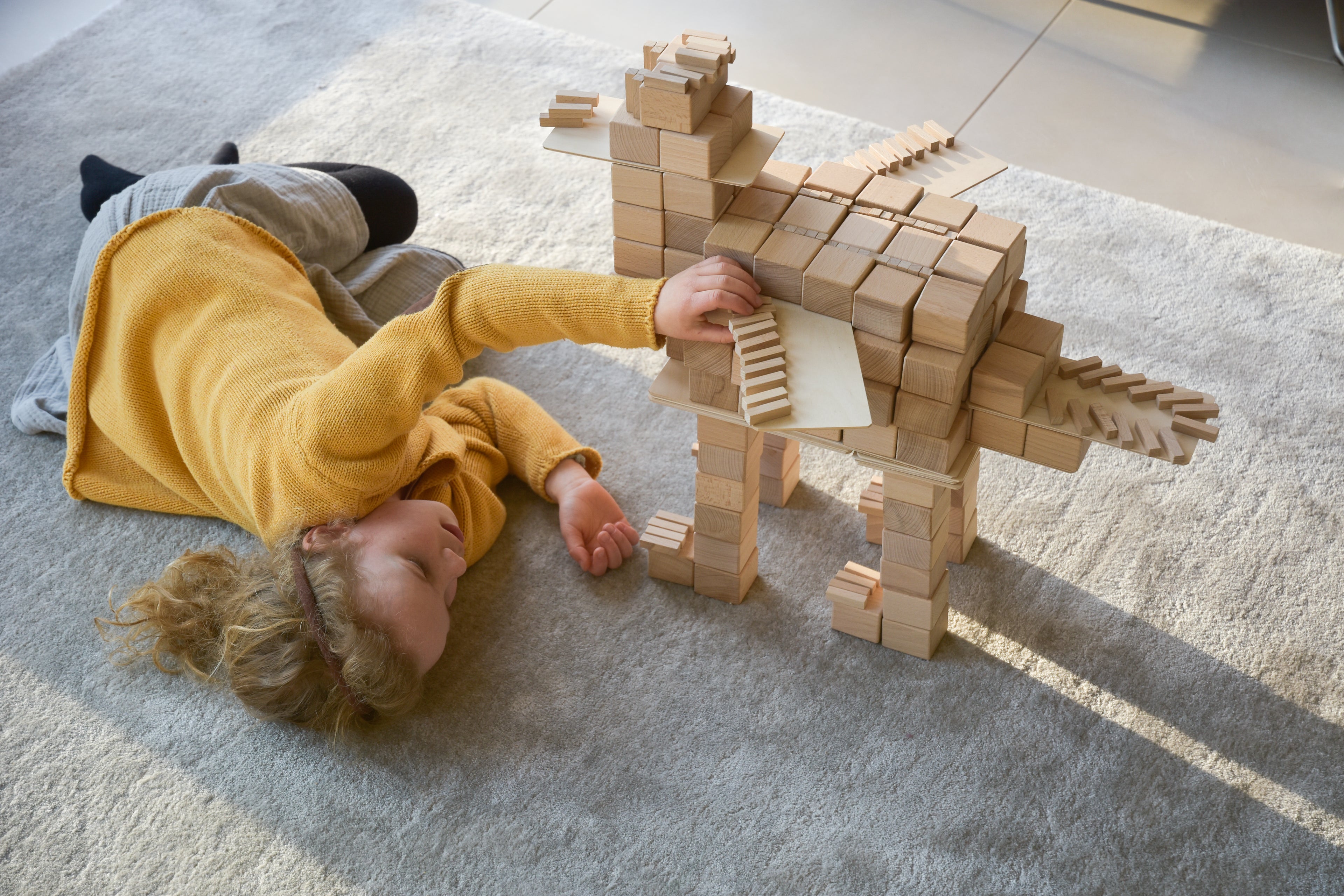 Kind baut liegend mit Just Blocks BASIC Big einen Drachen