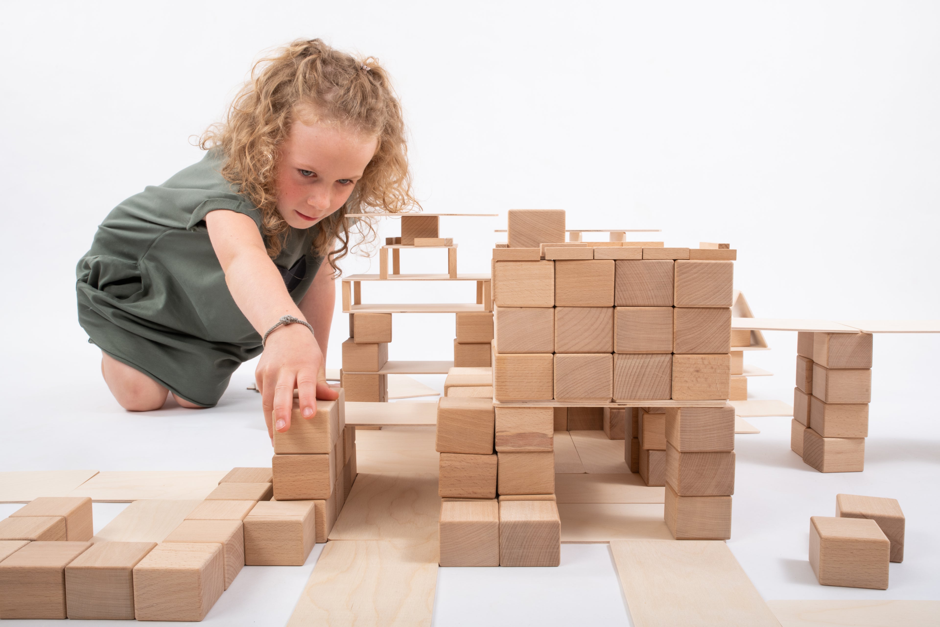 Kind baut mit dem Just Blocks BASIC Medium Holz-Lernsystem eine grosse Konstruktion