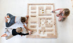 Drei Kinder bauen mit Just Blocks BASIC Big eine grosse Bauwelt aus Holzelementen