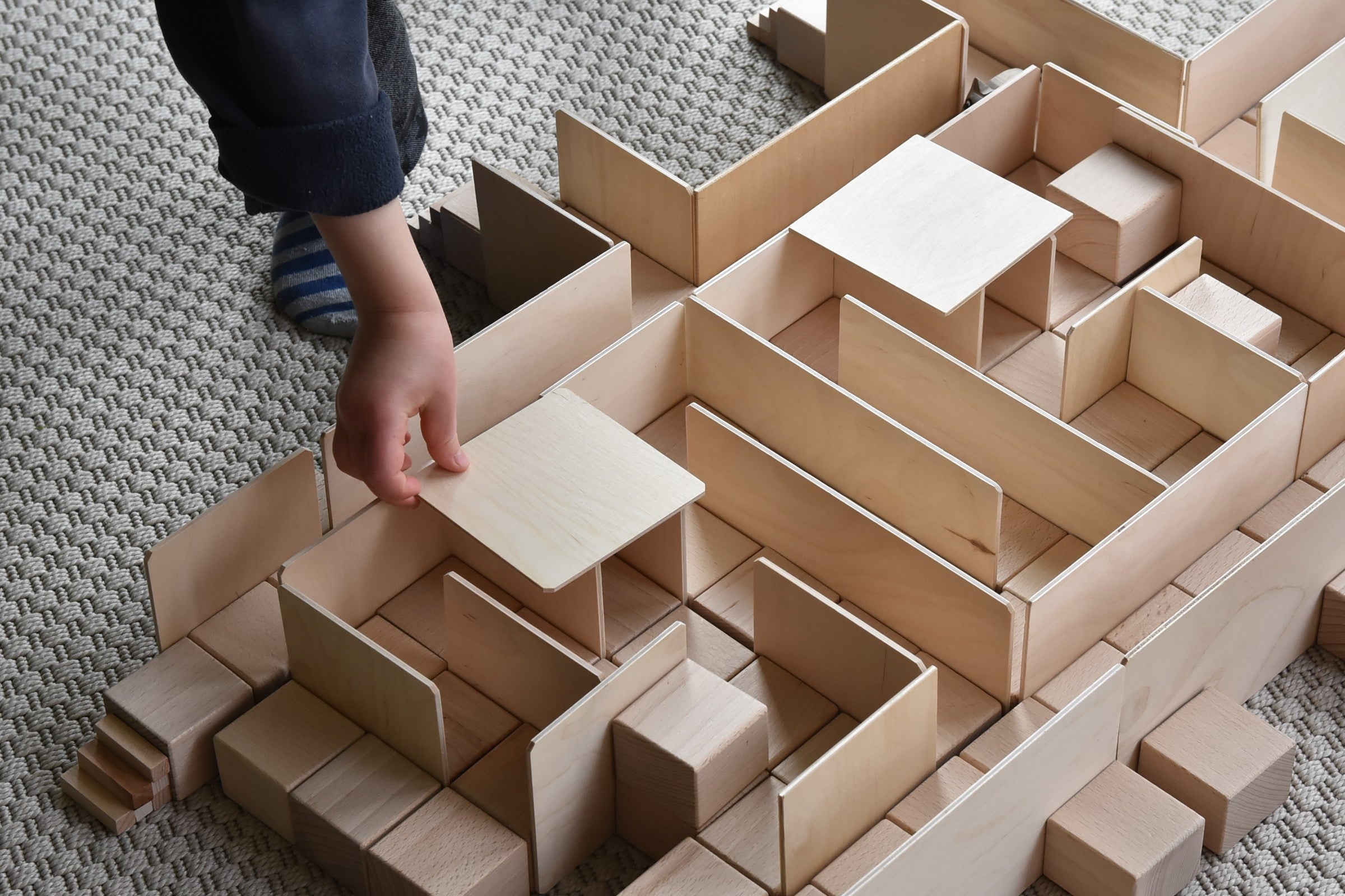 Kind baut mit Just Blocks BASIC Medium eine Holzkonstruktion