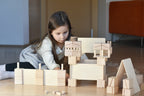 Kind spielt ruhig mit Just Blocks Smart Lines Holzbausteinen in einer natürlichen Wohnumgebung