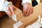 Kinderhände spielen mit einem Just Blocks Smart Lines Holzelement