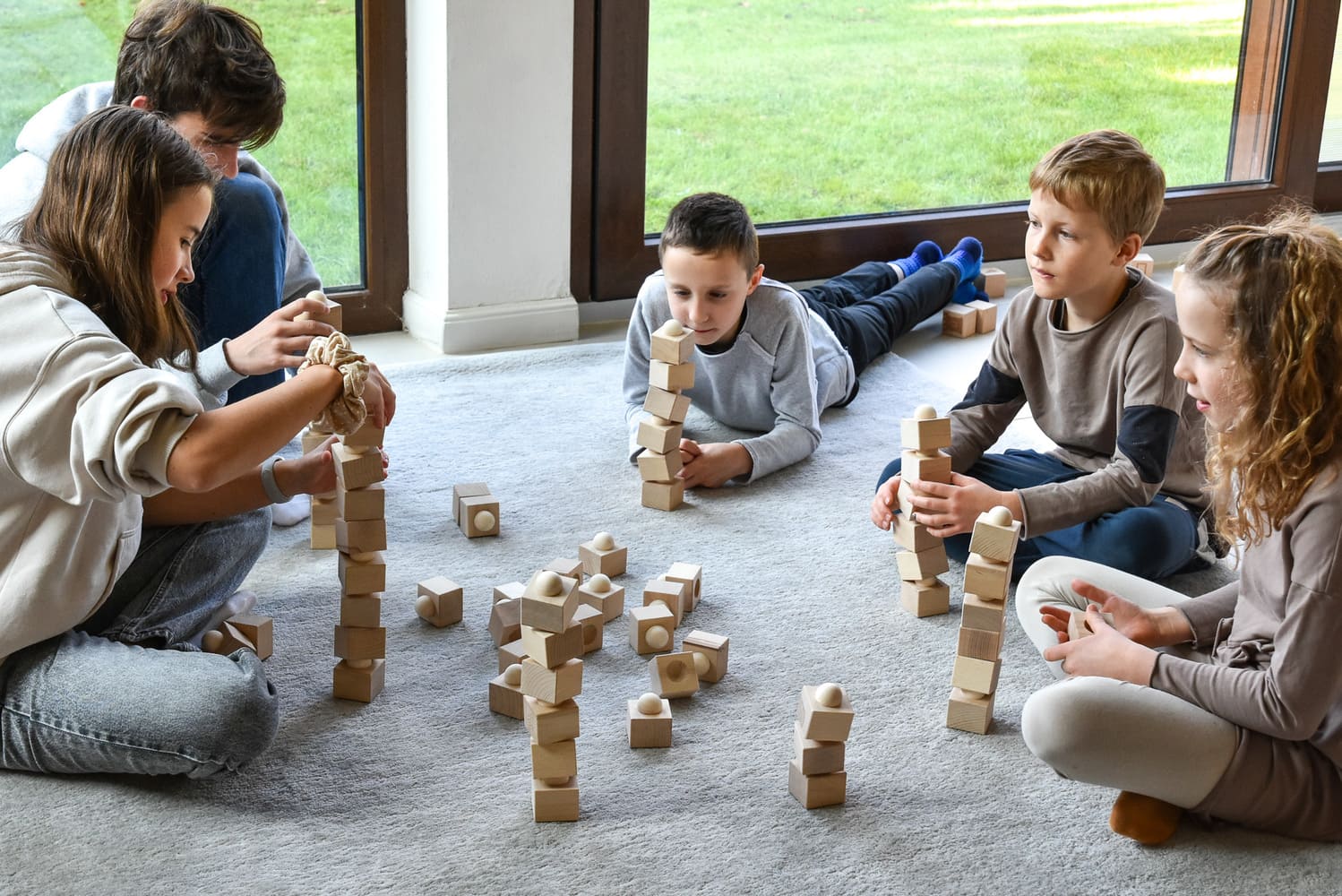 Kinder spielen gemeinsam mit dem Just Blocks Balance Tower Group Challenger Holz-Balancespiel