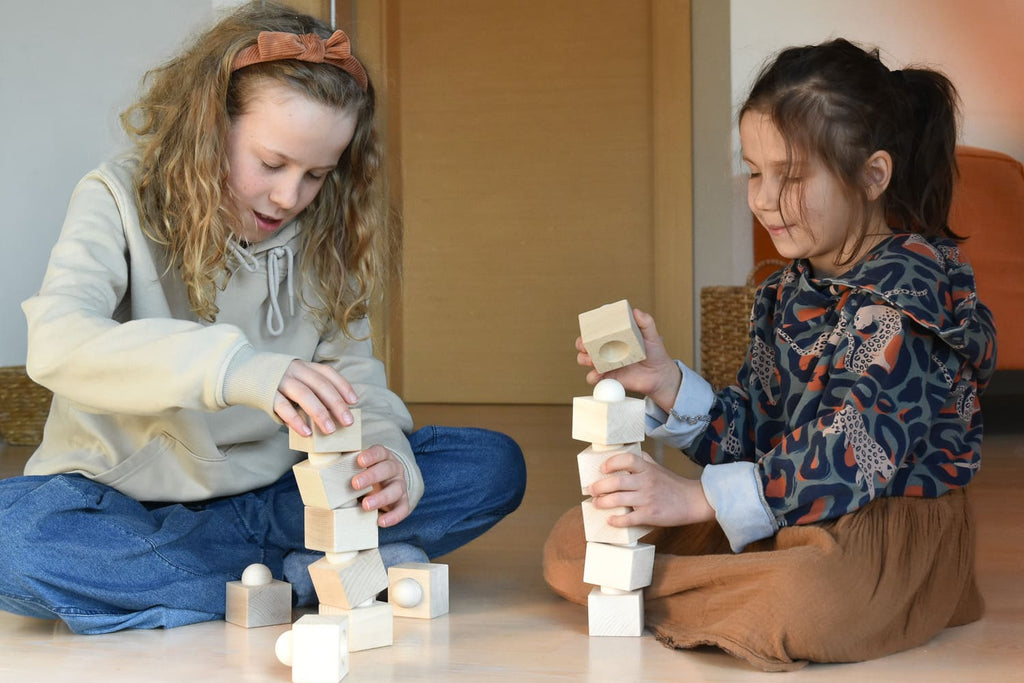 Zwei Kinder bauen mit dem Just Blocks Balance Tower Group Challenger balancierende Türme