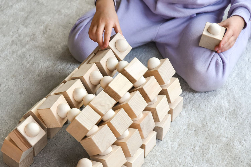 Kind baut eine grosse Balance-Konstruktion mit Würfeln und Halbkugeln
