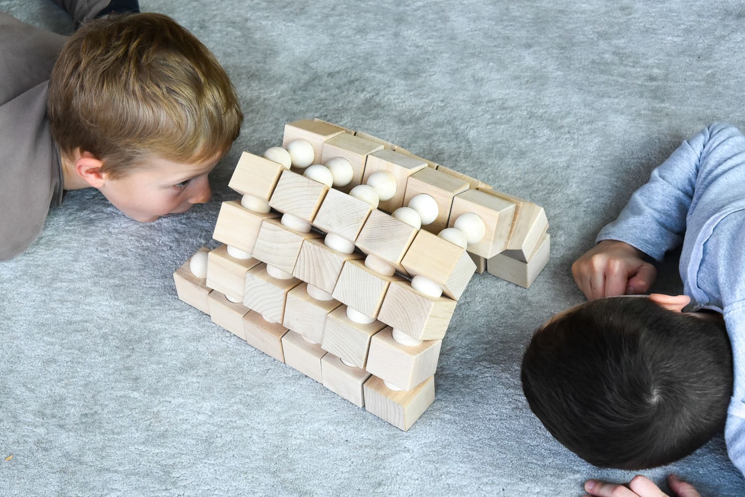 Kinder betrachten eine grosse Brücken-Bauidee aus Just Blocks Balance Tower Group Challenger Holzelementen